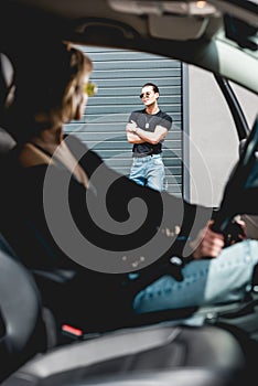Focus of stylish man looking at girl sitting in car