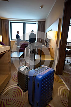 Focus on suitcases with blurred businessman and businesswoman near window