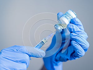 Focus on syringe, close up of doctor or nurse hands taking covid vaccination booster shot or 3rd dose from syringe photo