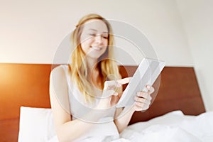 Focus on tablet, european young woman working happy remotely at white bed