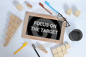 FOCUS ON THE TARGET text on blackboard with office accessories. Business motivation, inspiration concepts, pen and pencil case,