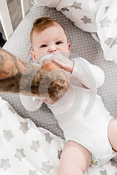 Focus of tattooed father feeding baby