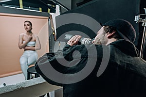 Focus of videographer filming female model in photo studio