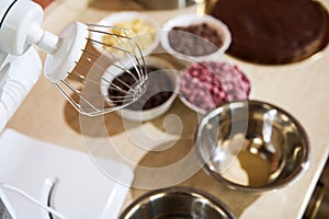 Focus on whisk of food processor on kitchen counter with blurred organic dark, milk, white and ruby pink chocolate chips