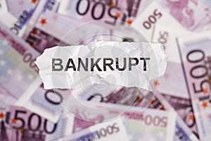 Focus on the word BANKRUPT on piece of torn white paper with blu