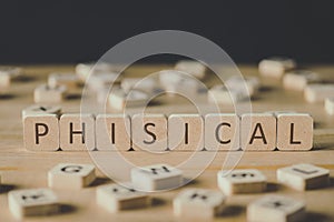 Focus of word phisical made of cubes surrounded by blocks with letters on wooden surface isolated on black