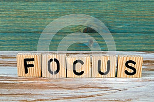 Focus. Word from wooden letters on a white and green background