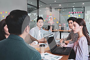 Focus on young asian man having question in group brainstorm meeting in office.Businesspeople discussing with paperwork for