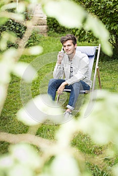 Focus on young man waiting on telephone in lush foliage