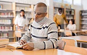 Focused adult latin american student studying in library