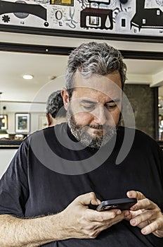 Focused adult man browsing smartphone in shop