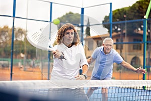 Focused adult man playing doubles paddle tennis