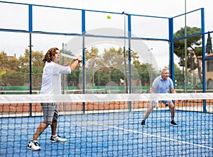 Focused adult man playing doubles paddle tennis