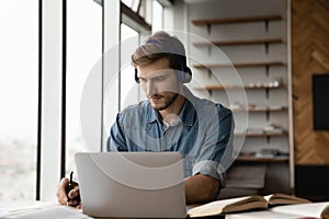 Focused adult student guy in headphones listening to learning seminar