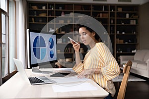 Focused African American businesswoman holding loudspeaker conversation, working on computer.