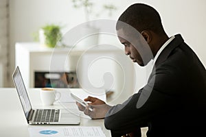 Focused African American checking phone email in office