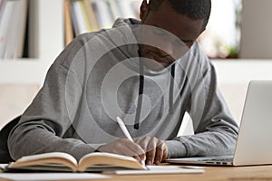 Focused african American guy make notes studying on laptop