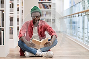 Focused African American guy preparing materials for upcoming lecture reading book in university