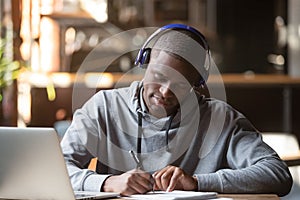 Concentrated black male student in Bluetooth headphones studying photo