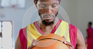 Focused African American man holding a basketball in a gym