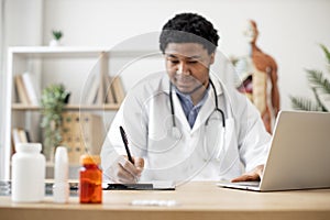 Physician typing on laptop and making notes in clinic