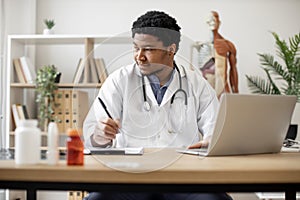 Physician typing on laptop and making notes in clinic