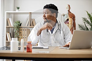 Physician typing on laptop and making notes in clinic