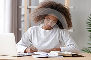 Focused african american school girl studying writing essay doing homework photo