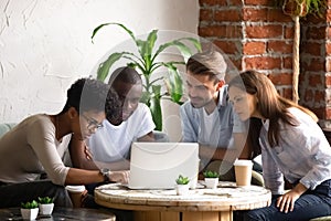 Focused African American woman with friends using laptop