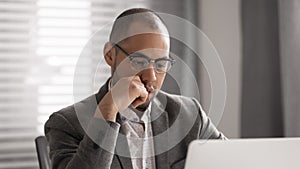 Focused african businessman thinking solving business problem looking at laptop