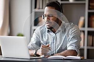 Focused african businessman wear headphones study online watching webinar