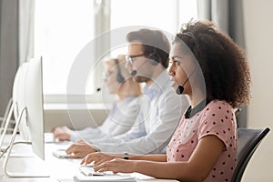 Focused african call center operator consulting customer looking at computer