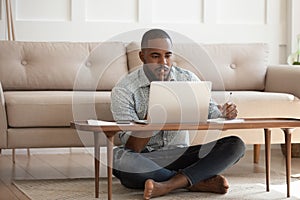 Focused african man studying or working on laptop at home