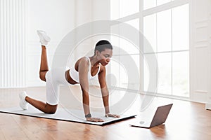 Focused African Woman In Sportswear Doing Donkey Kicks Exercise