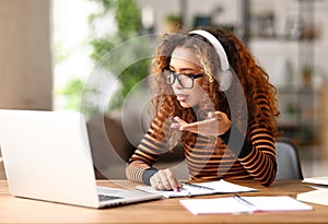 Focused afro american female having video call while working remotely or studying online on laptop from home