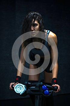 Focused afro-arab girl riding indoor bike during cycling class