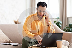 Focused Arab man working and talking on phone at home