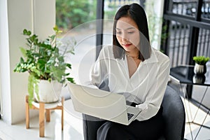 Focused asian businesswoman working on her business tasks on laptop, remote working at cafe