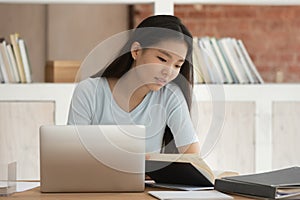 Focused Asian girl prepare for exam with book and laptop