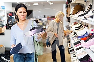 Focused asian woman chooses sports sneakers