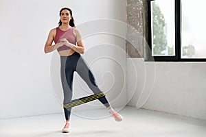 Focused athlete woman in activewear doing stretching work out with elastic band