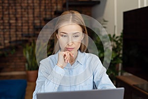 Focused attractive woman looking at laptop monitor