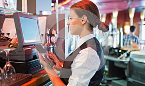 Focused barmaid using touchscreen till