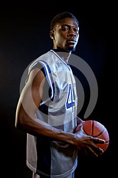 Focused basketball player holds ball in studio