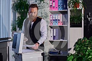 focused bearded businessman photocopying documents on