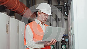 Focused bearded specialist with modern computer checking machines at plant room