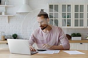 Focused bearded young hipster tenant man calculating mortgage fees