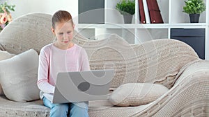 Focused beautiful child girl chatting in social network typing message using laptop pc medium shot