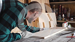 Focused bold carpenter with vintage moustache at work with wooden plank