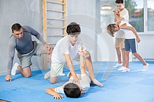 Focused boy learning effective self defence techniques in sparring with boy, practicing painful pronating wristlock on